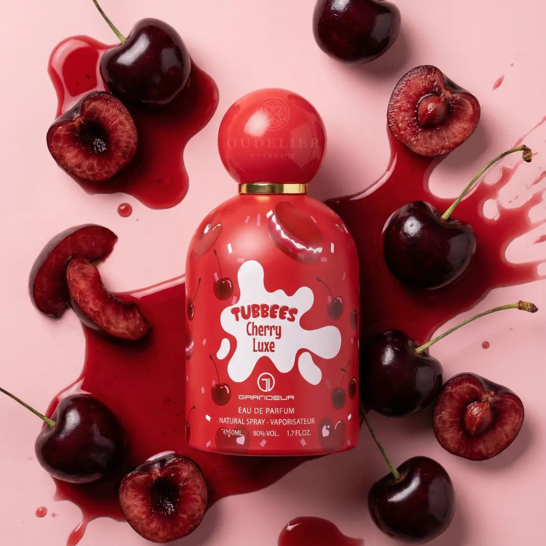 Red perfume bottle labeled "Tubbees Cherry Luxe" amidst fresh cherries and juice on a light pink background, creating a vibrant and fruity mood.
